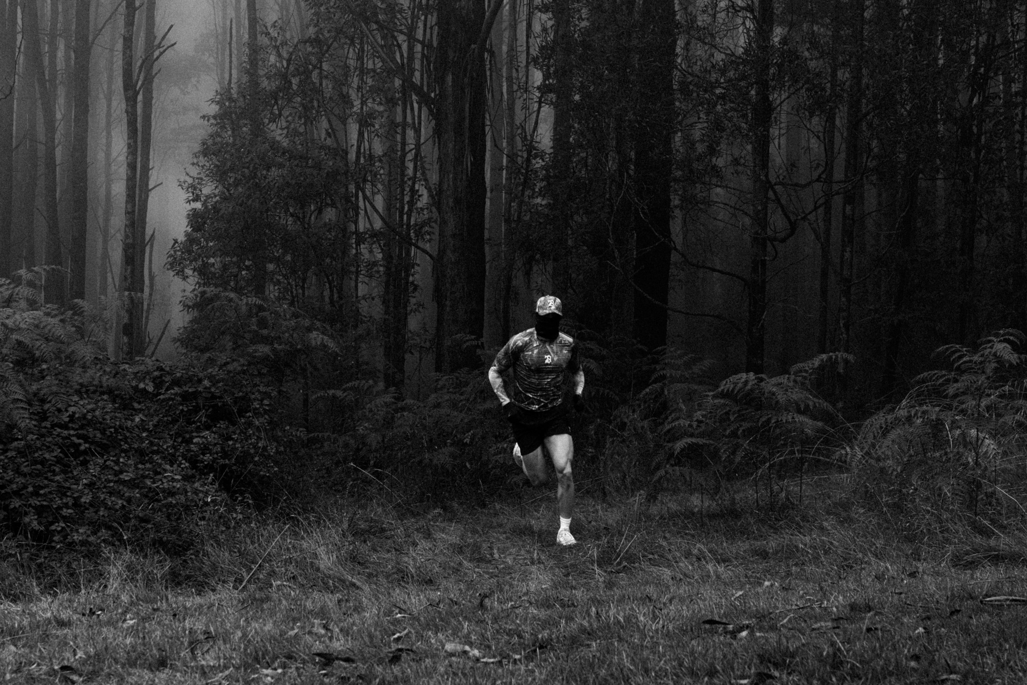 Man running along a winding road in a foggy setting, surrounded by nature.